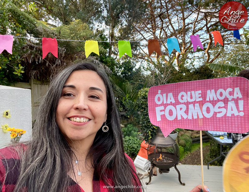 Ange con cartel óia que moça formosa frente a estufa a leña en festa junina.